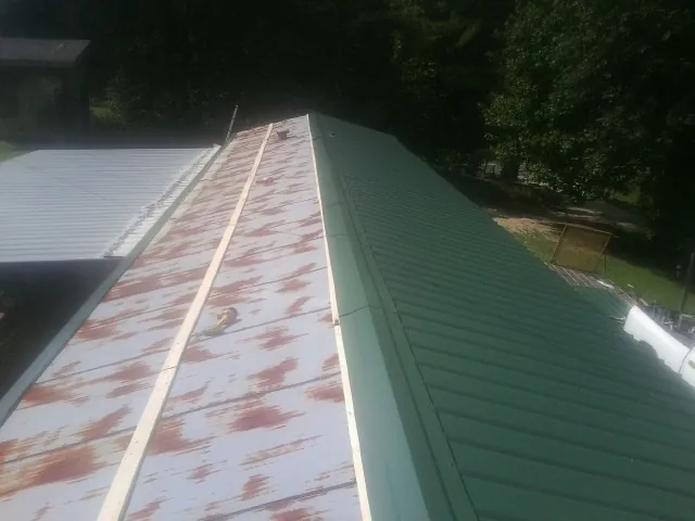 Old rusted panels beside newly installed green metal roofing — Wind Damage Roof Repair by Roofing Brothers in Tracy