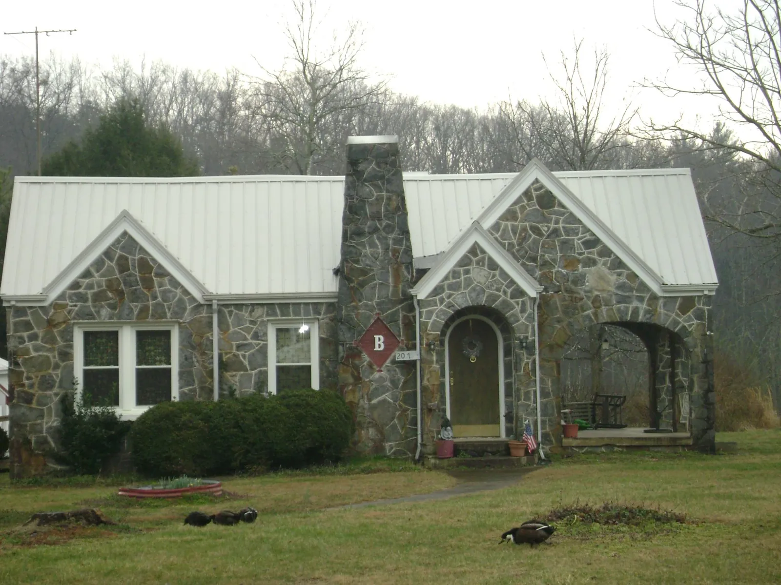 White metal roof on a stone cottage with steep gables in Tracy