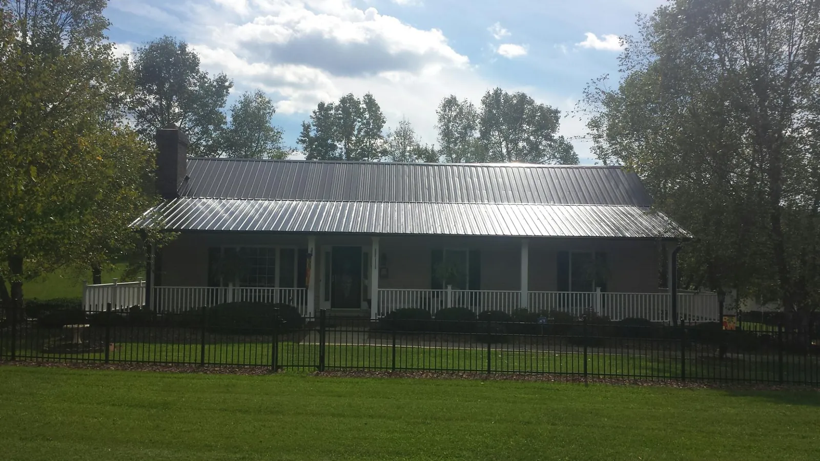 Gray metal roof on a brick ranch with a full width front porch — Gutter Guard Installation work by our crew in Tracy